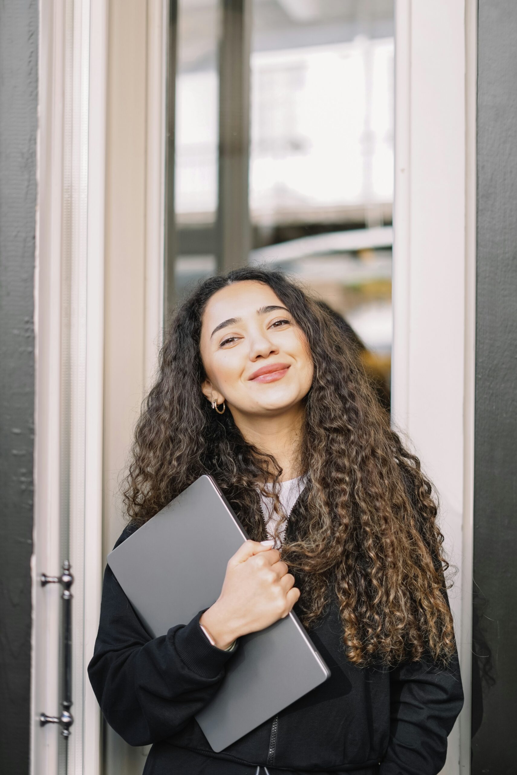 Junge motivierte Frau hält Laptop in der Hand und lächelt, Symbolbild für Lehrgang Lektorat und Korrektorat, Weiterbildung im Text- und Sprachbereich, Online-Kurs für Textkorrektur und Lektorat